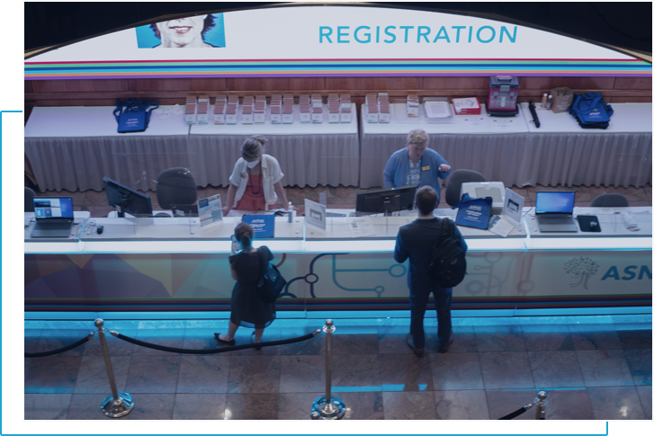 two people being registered at the front desk for the ASNR annual meeting