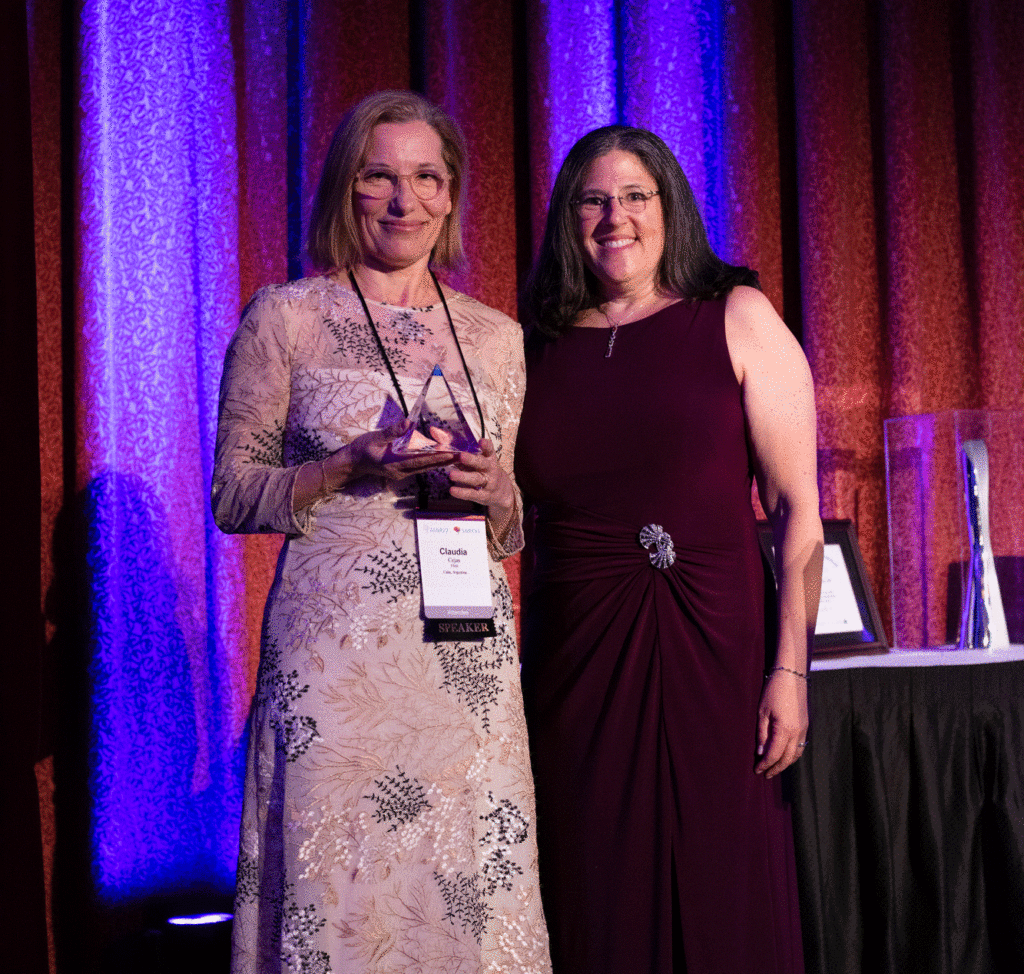 Two women at the ASNR awards holding a glass pyramid shaped award